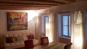 A cozy living room with a sofa, a dining table, and a colorful painting on the wall. - Romantic,central Situated 75m2 Flat (Salzburg)