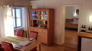 A cozy room with a wooden dining table, red chairs, a cabinet with glass doors, and a bed in the background. - Romantic,central Situated 75m2 Flat (Salzburg)