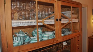 A wooden cabinet with glass doors containing various glassware and striped ceramic dishes. - Romantic,central Situated 75m2 Flat (Salzburg)