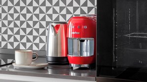 A kitchen with a microwave, a red coffee maker, and a coffee cup on a tray.
