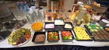 Une table de buffet proposant une variété de plats, de boissons et d’ustensiles.