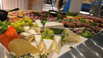 A variety of cheeses, meats, and fruits on a buffet table.