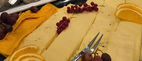 Una mesa de buffet con diversas opciones de comida, incluyendo quesos, frutas y carnes.