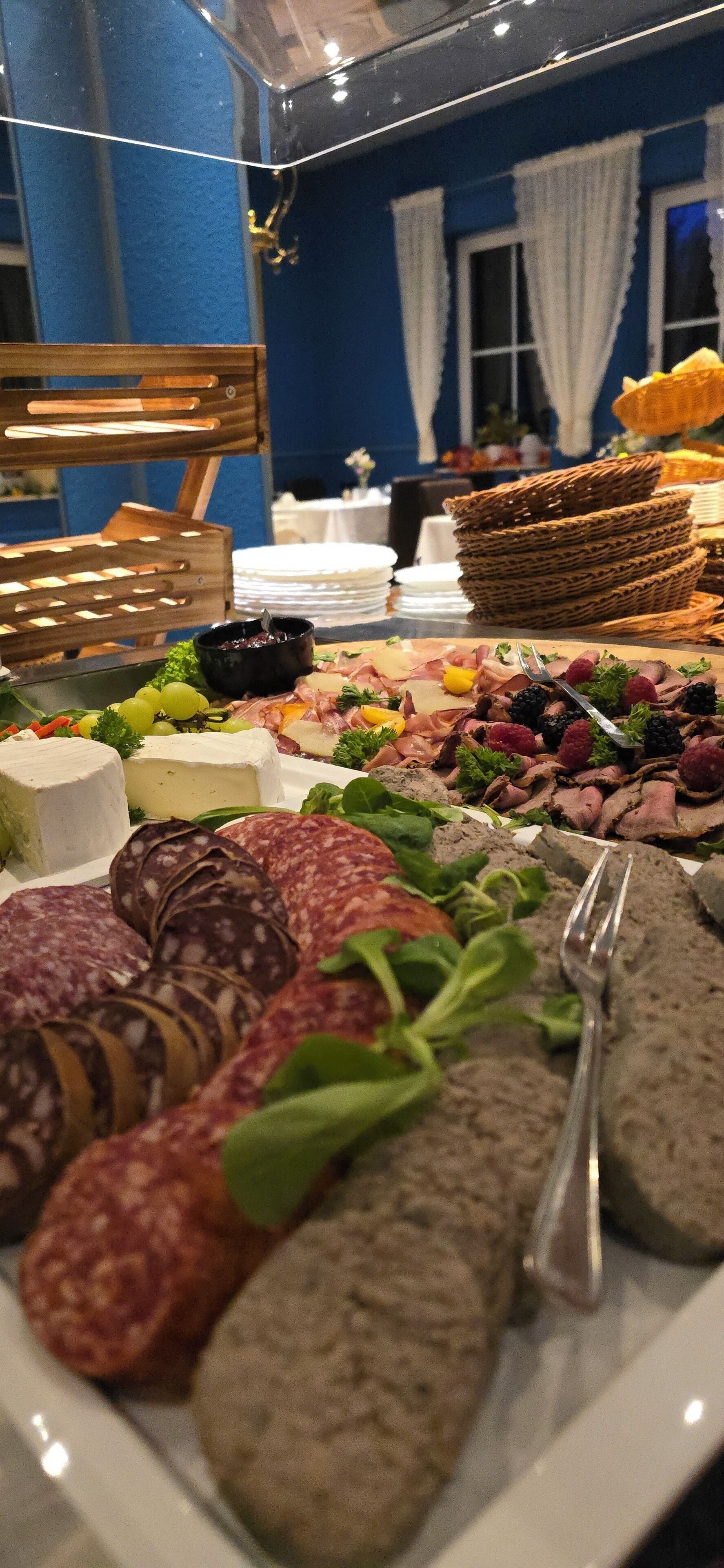 En buffet med forskellige oste, pålæg og frugter.
