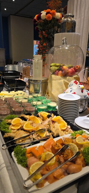 A buffet with various food items including meats, fruits, and desserts.