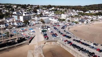 A coastal town with a parking lot filled with cars, a beach, and residential buildings.