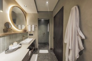 Bathroom features a large oval mirror, white sink, and dark door.
