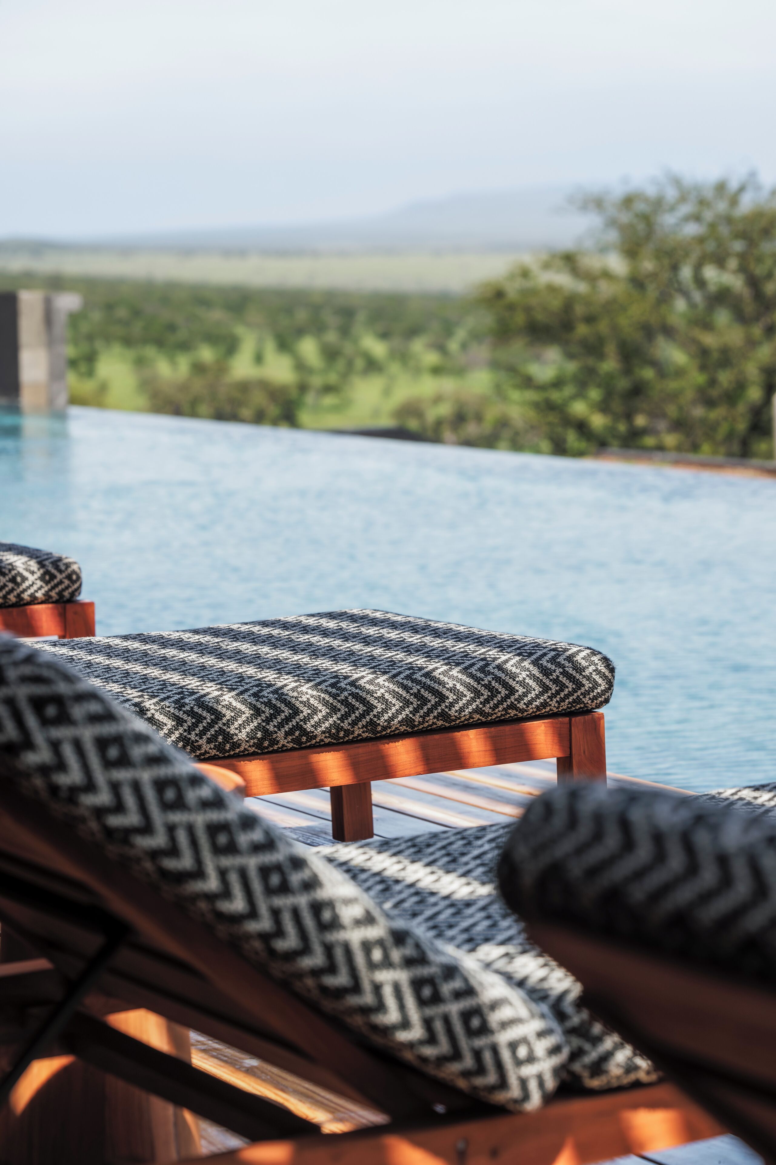 Área de piscina com espreguiçadeiras e vista para uma paisagem natural.