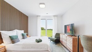 Un dormitorio moderno con una cama grande, un televisor, un armario de madera y vistas al exterior.