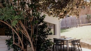 An outdoor patio with a table and chairs, surrounded by a wooden fence and a tree. - Treelined retreat Lenah Valley (Lenah Valley)