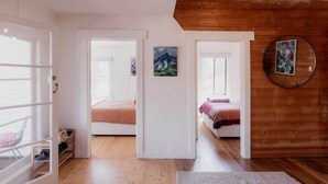 A bedroom with two beds, wooden flooring, and a large mirror on the wall. - Treelined retreat Lenah Valley (Lenah Valley)