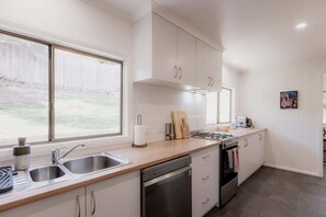 Enjoy cooking in this well-equipped kitchen with a large window, stainless steel sink, and modern stove.