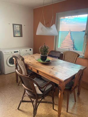 Enjoy meals in this dining area with a table for four, wicker chairs, and a potted plant.