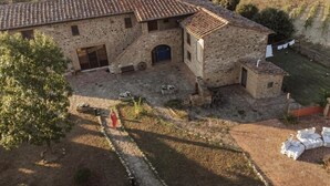 A stone building with a tiled roof, a central courtyard, and a small garden area. - MATRIMONIAL ROOM with private bathroom, (Radicondoli)