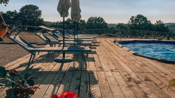 A wooden deck with lounge chairs and umbrellas, overlooking a swimming pool. - MATRIMONIAL ROOM with private bathroom, (Radicondoli)