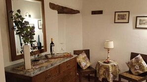 A room with a wooden dresser, a mirror, a table with a lamp, and two chairs with floral cushions. - MATRIMONIAL ROOM with private bathroom, (Radicondoli)