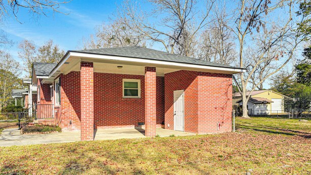 A single-story brick house with a covered porch, a front door, and a small window. - Conveniently Located North Charleston Home! (North Charleston)