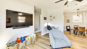 A modern living room with a flat-screen TV, a ceiling fan, a dining area with chairs, and a small table. - Conveniently Located North Charleston Home! (North Charleston)