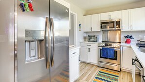 A modern kitchen with stainless steel appliances, white cabinets, and a colorful rug. - Conveniently Located North Charleston Home! (North Charleston)