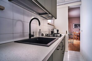 A modern kitchen with a black sink, stainless steel appliances, and a white countertop.