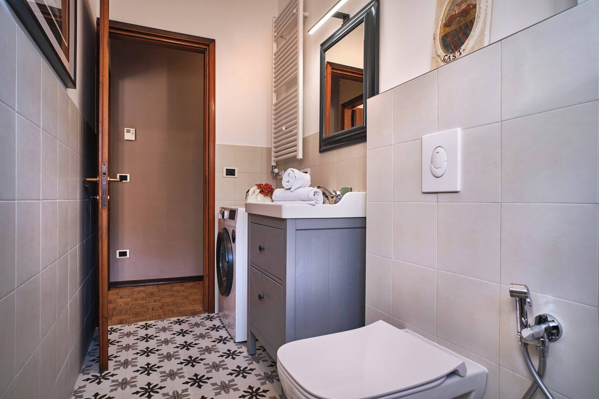 A compact bathroom with a toilet, sink, and a mirror.