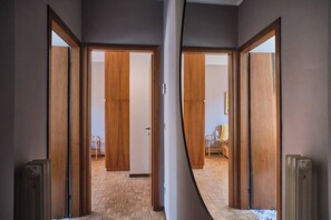 Um corredor com portas de madeira que dão para um quarto com padrão de piso em espinha de peixe.