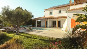 A modern house with a swimming pool, patio furniture, and a garden.