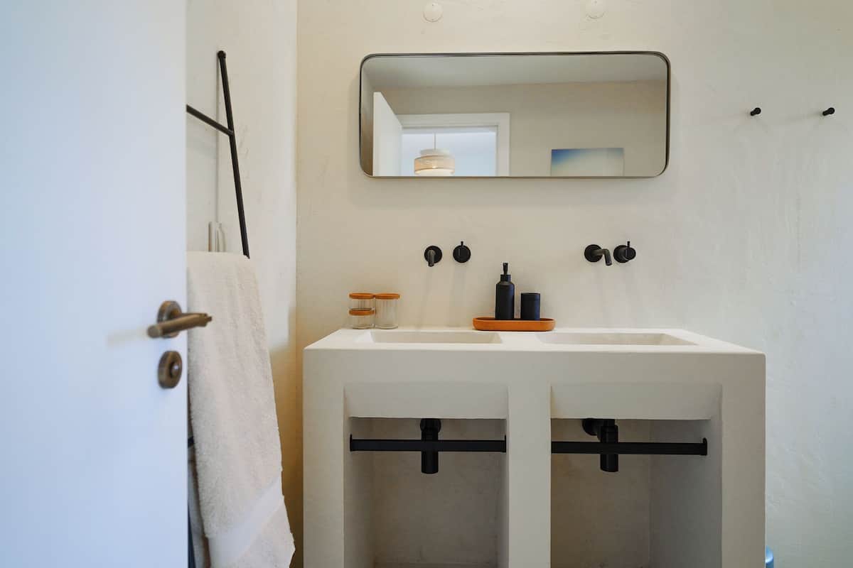 Une salle de bain avec un lavabo blanc, un miroir et deux porte-serviettes fixés au mur.