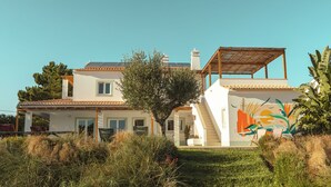 A two-story house with a covered patio, a staircase, and a mural on the side.