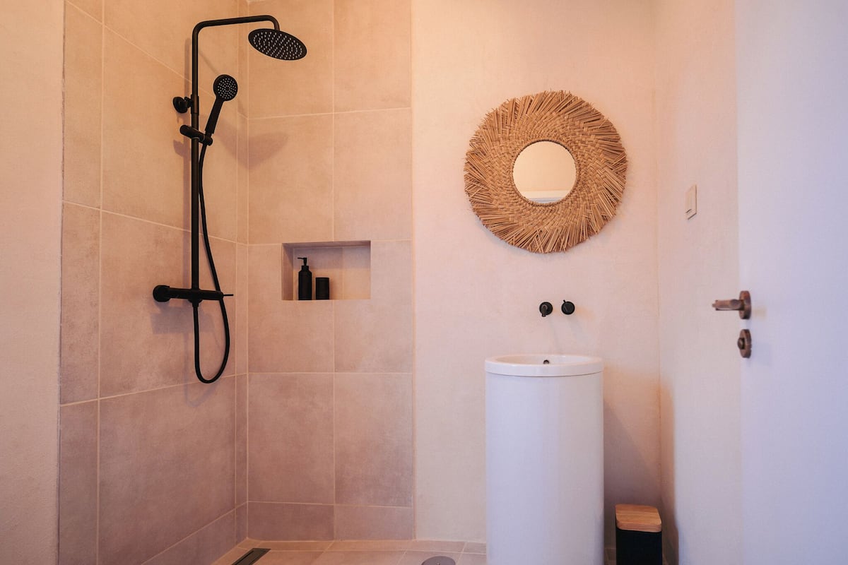 Une salle de bain avec une douche, un lavabo et un miroir.