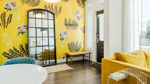 A room with a yellow patterned wall, a round table, a yellow sofa, and a wooden bench. - Urban Luxury on Washington Park | Rooftop & Parkin (Cincinnati)