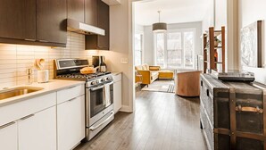 A modern kitchen with dark wooden cabinets, a stainless steel sink, and a large stove. - Urban Luxury on Washington Park | Rooftop & Parkin (Cincinnati)