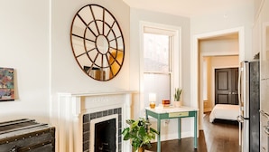 A modern kitchen with a fireplace, a large mirror, and a dining area with a table and chairs. - Urban Luxury on Washington Park | Rooftop & Parkin (Cincinnati)