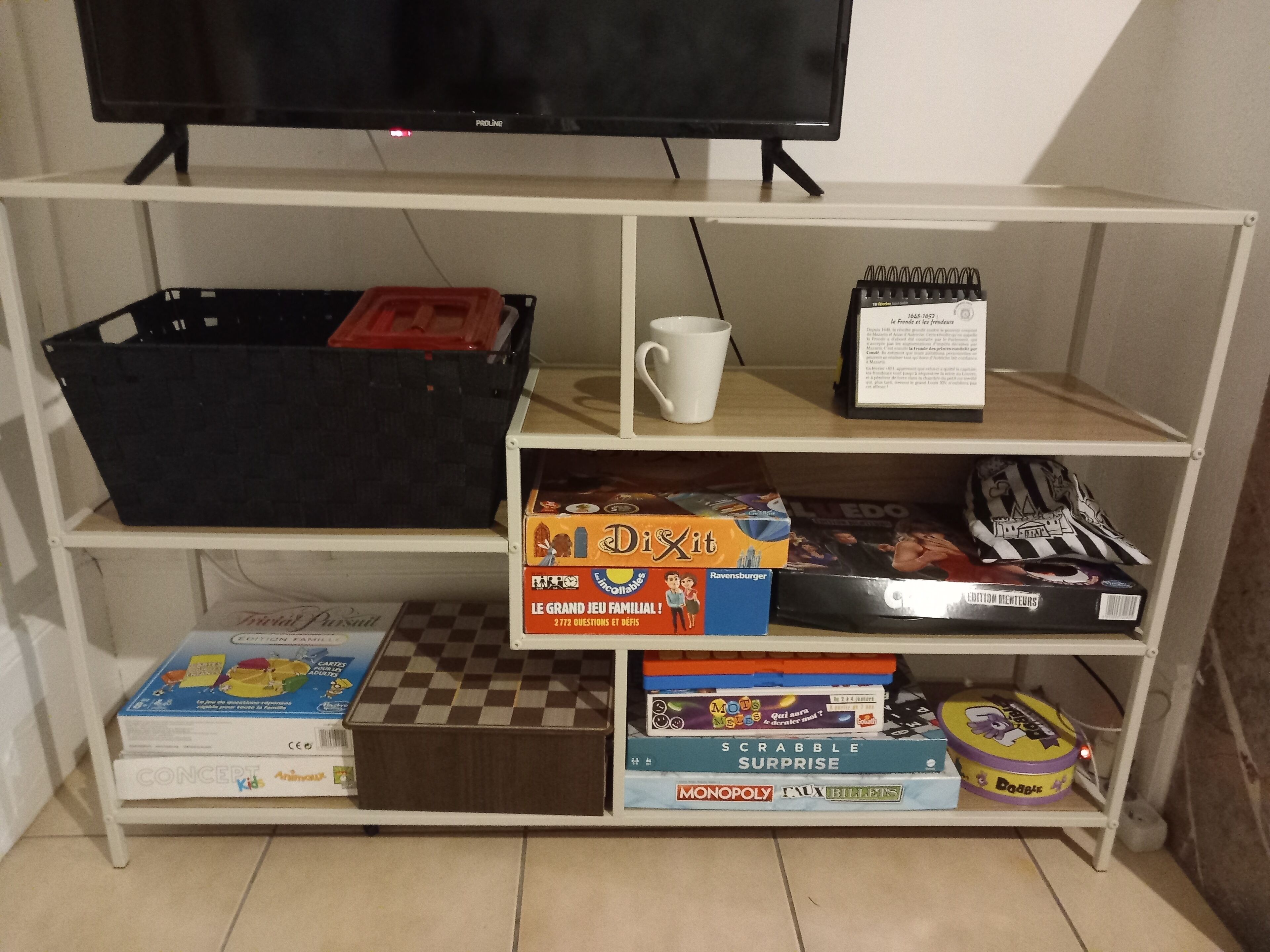 A shelf with various board games and a television above.