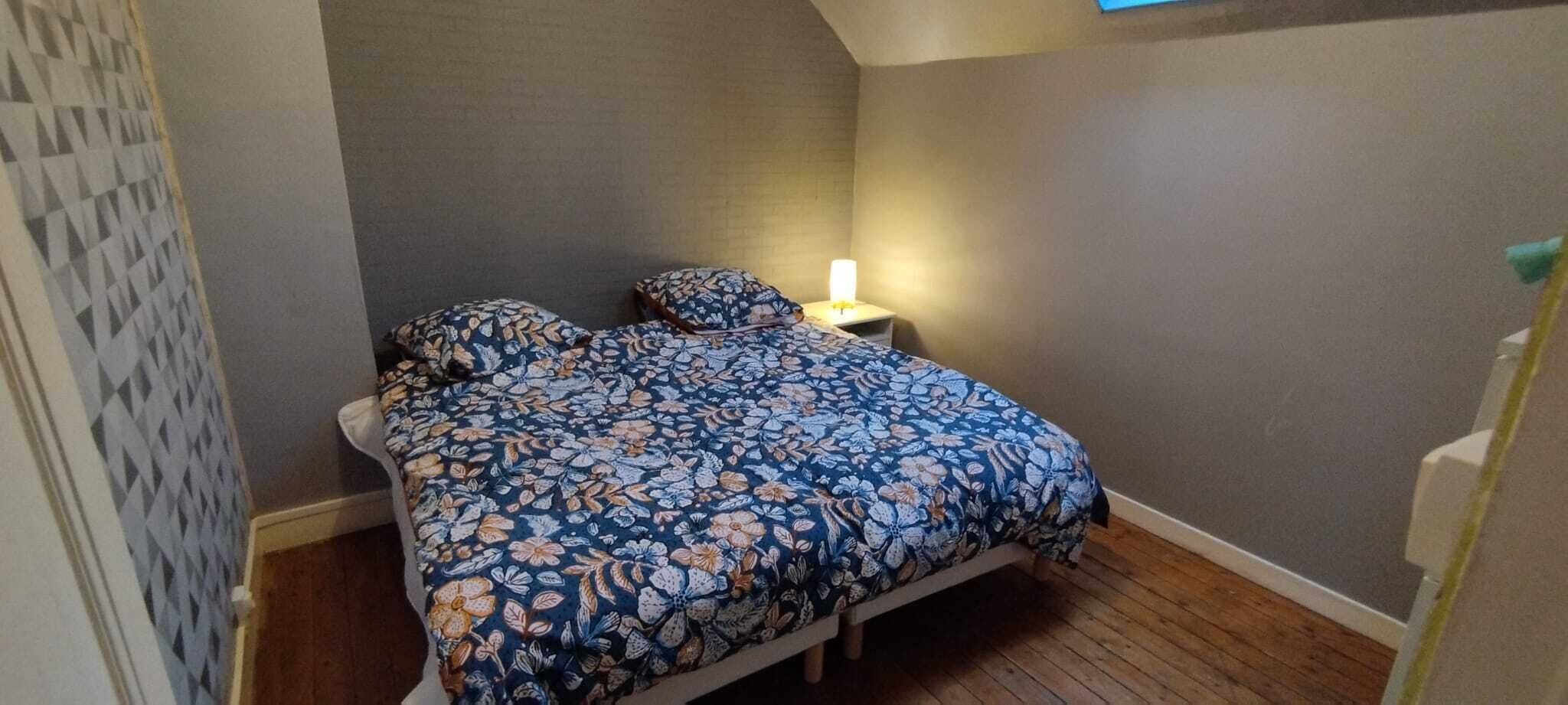 Un dormitorio con cama, mesita de noche, lámpara y pared con diseño.