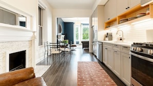 A modern kitchen with white cabinets, a stove, and a dining area with a fireplace.
