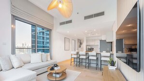 Un salon moderne avec un canapé, une table basse et une vue sur la ville grâce à de grandes fenêtres.