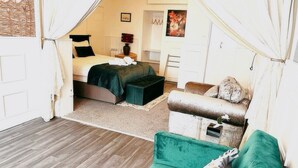 Une chambre confortable avec un lit, un canapé vert et une petite table.