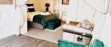 A cozy bedroom with a bed, a green sofa, and a small table.