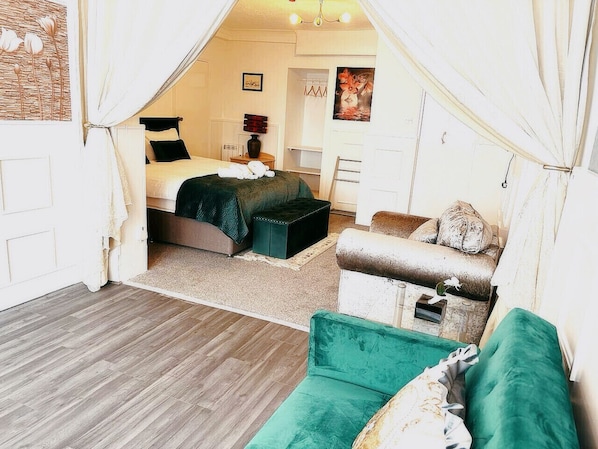 Une chambre confortable avec un lit, un canapé vert et une petite table.