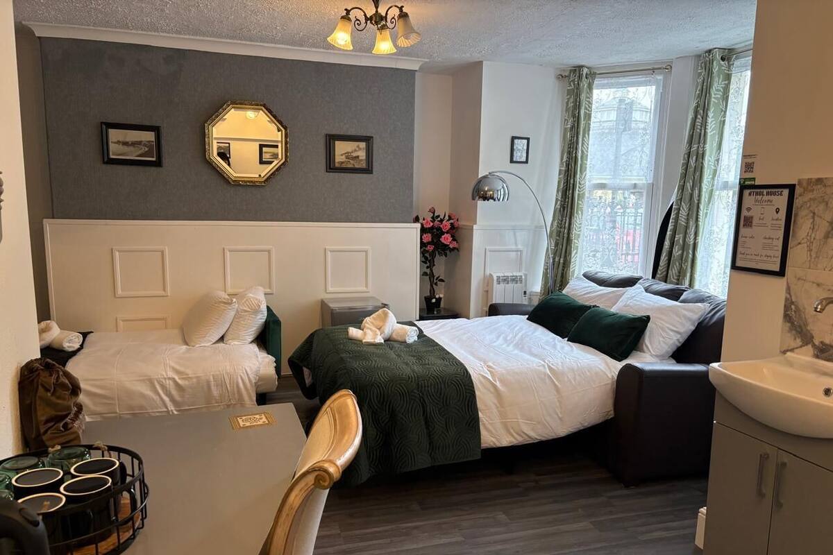 A hotel room with a bed, a desk, a chair, a small table, and a cabinet.