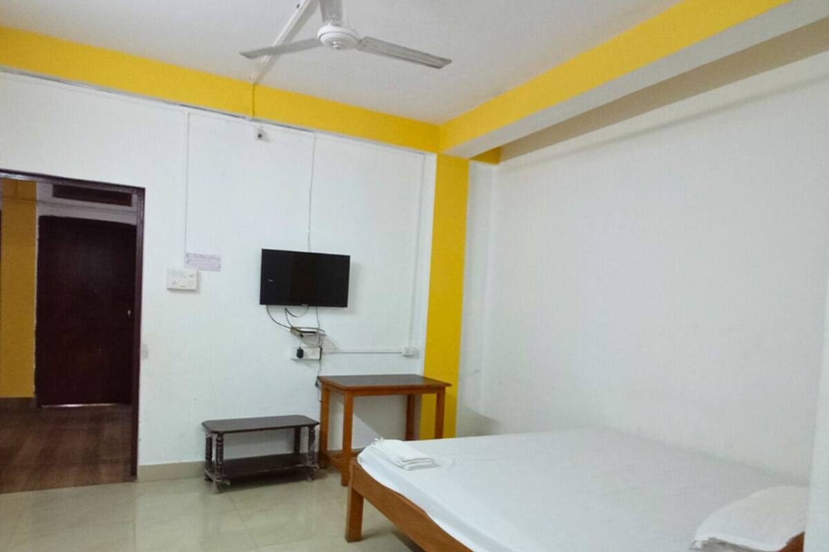 A room with a bed, a ceiling fan, a television, and a small table.