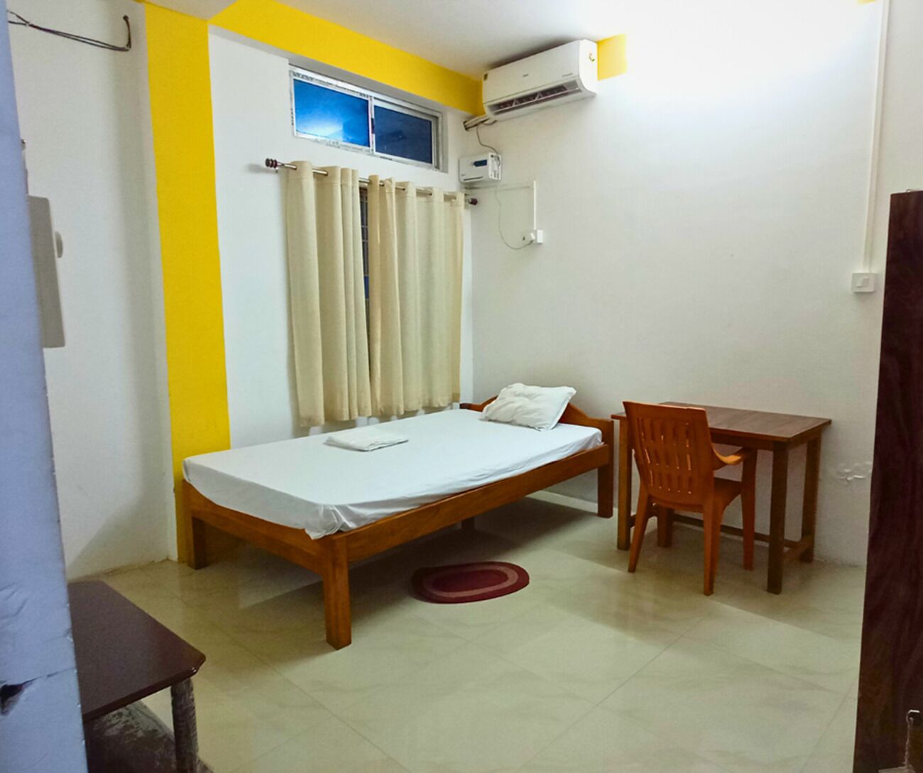 A small room with a bed, a table, and a chair.
