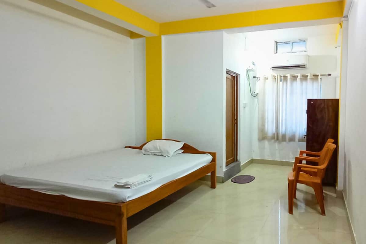 A room with a bed, a chair, a ceiling fan, and a door leading to a bathroom.