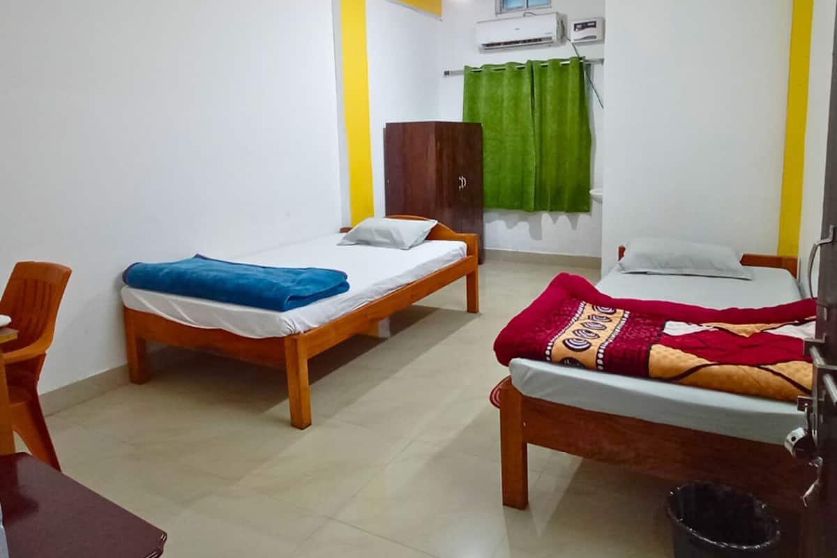 A room with two wooden beds, a desk, a chair, a wardrobe, and a green curtain.