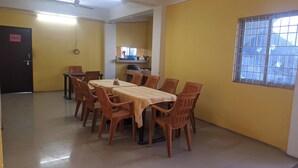 Ein Essbereich mit Tisch und Stühlen, dahinter eine Küche und ein Fenster mit Gitterstäben.