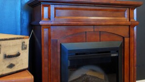 A fireplace with a wooden mantel, a lamp on top, and several vintage suitcases stacked beside it. - Magistrate Rm, The Lodge at Old City Hall (Jefferson City)