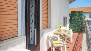 A balcony with a table and chairs, a bottle of wine, and a green leafy wall. - Cozy apartment in Chianchitta - Pallio with WiFi (Chianchitta - Pallio)