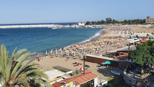 A beach with numerous umbrellas and sun loungers, a clear view of the sea, and a row of buildings along the shore. - Cozy apartment in Chianchitta - Pallio with WiFi (Chianchitta - Pallio)