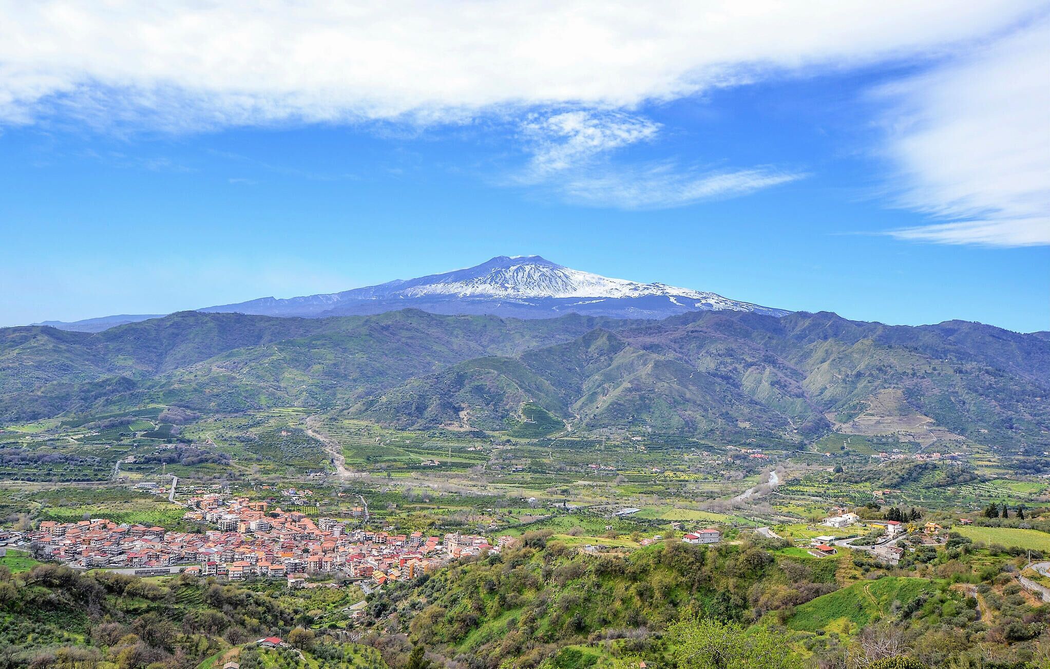 Un pueblo situado en un valle, con una montaña imponente al fondo.